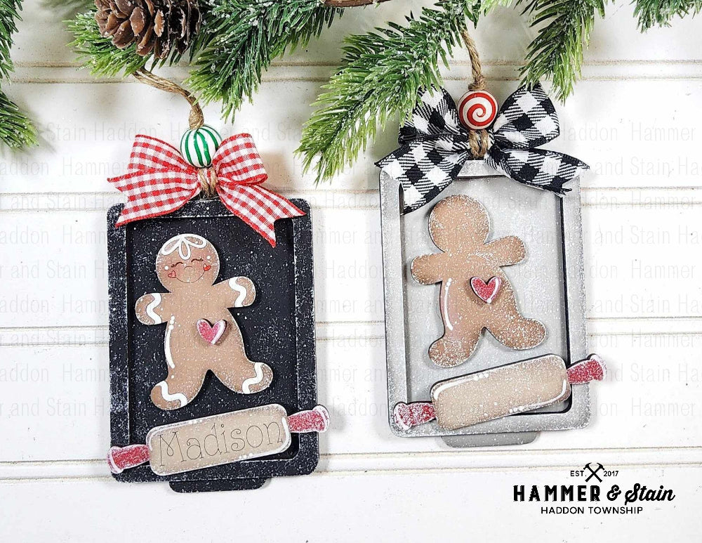 Two Christmas ornaments with gingerbread men and decorative bows on a white background.