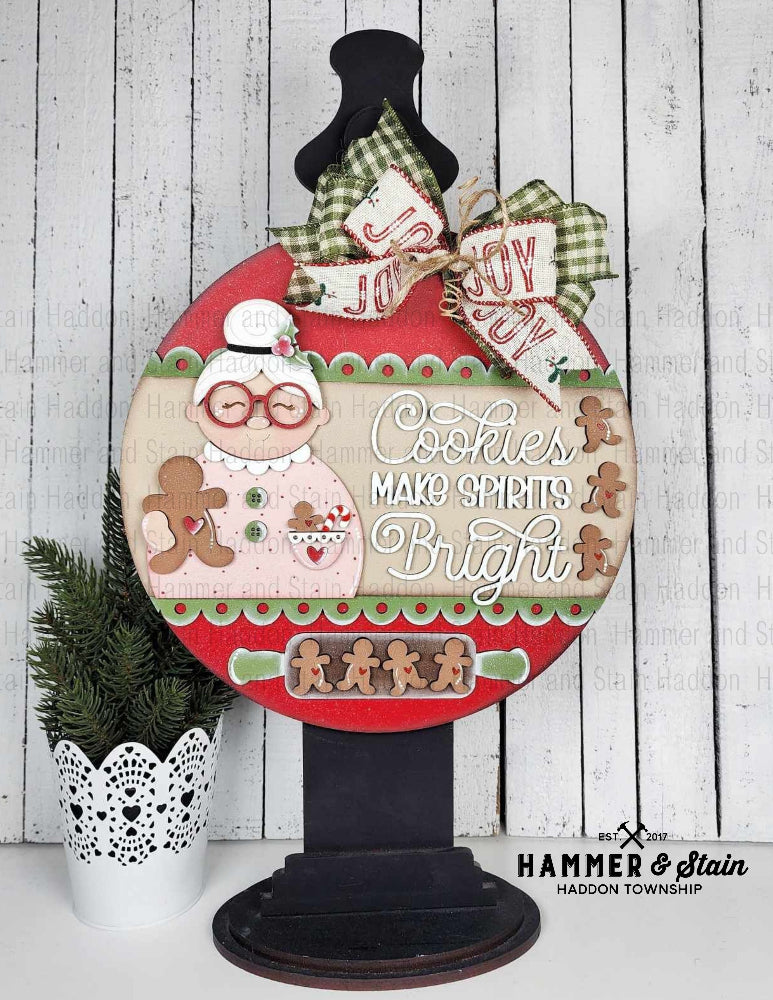 Mrs. Clause Christmas door Hanger with gingerbread theme and text on a stand.