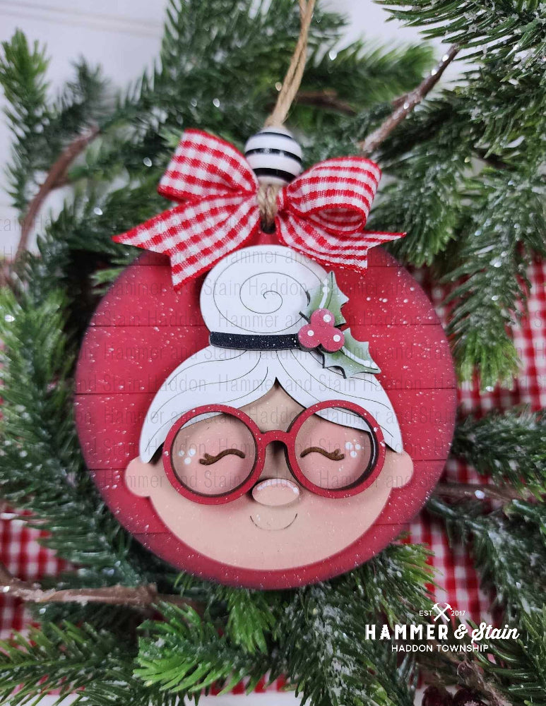 Mrs. Clause ornament with a face design, red bow, and 'Hammer & Stain' branding on a Christmas tree.