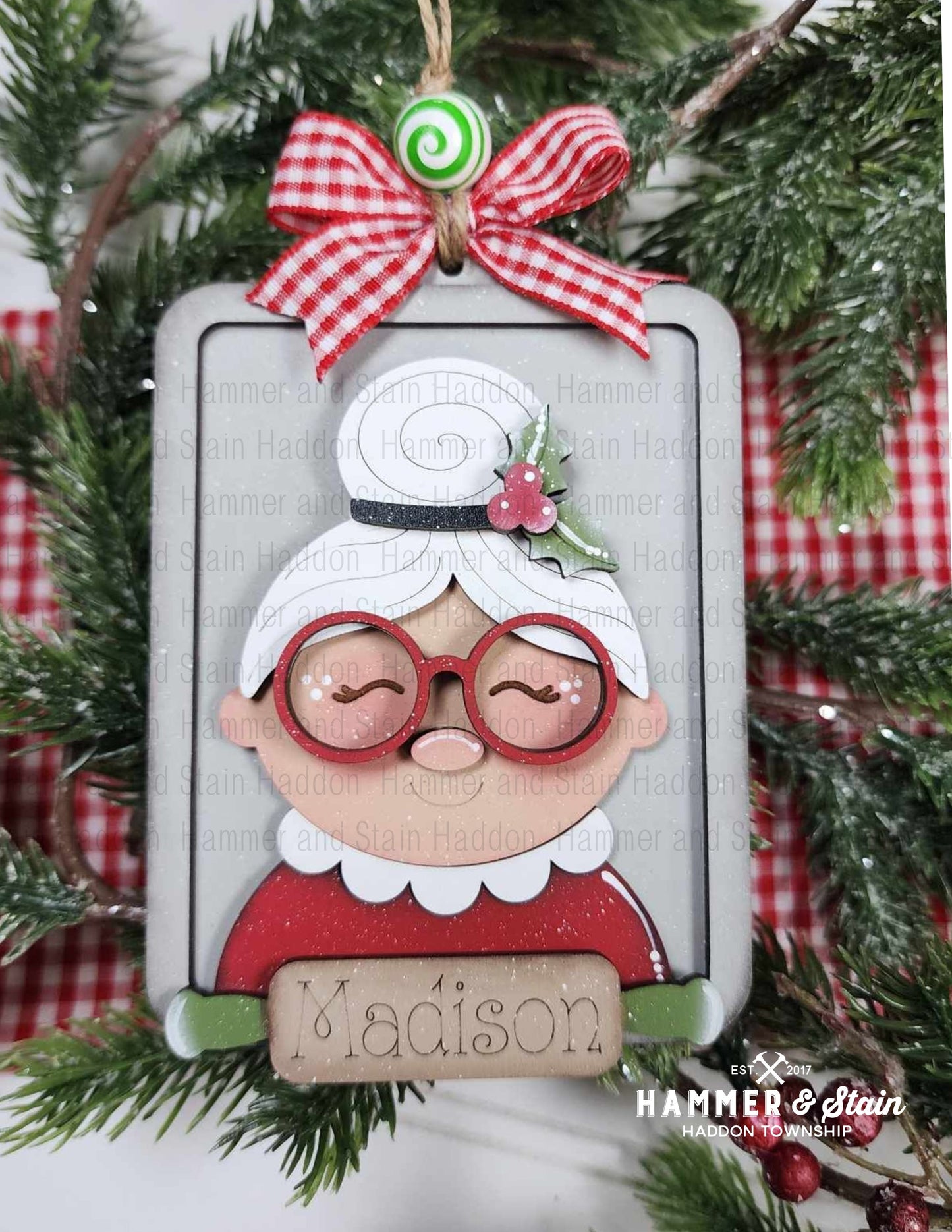 Mrs. Clause baking ornament wearing glasses and a red outfit with a cookie sheet background hanging on a tree.