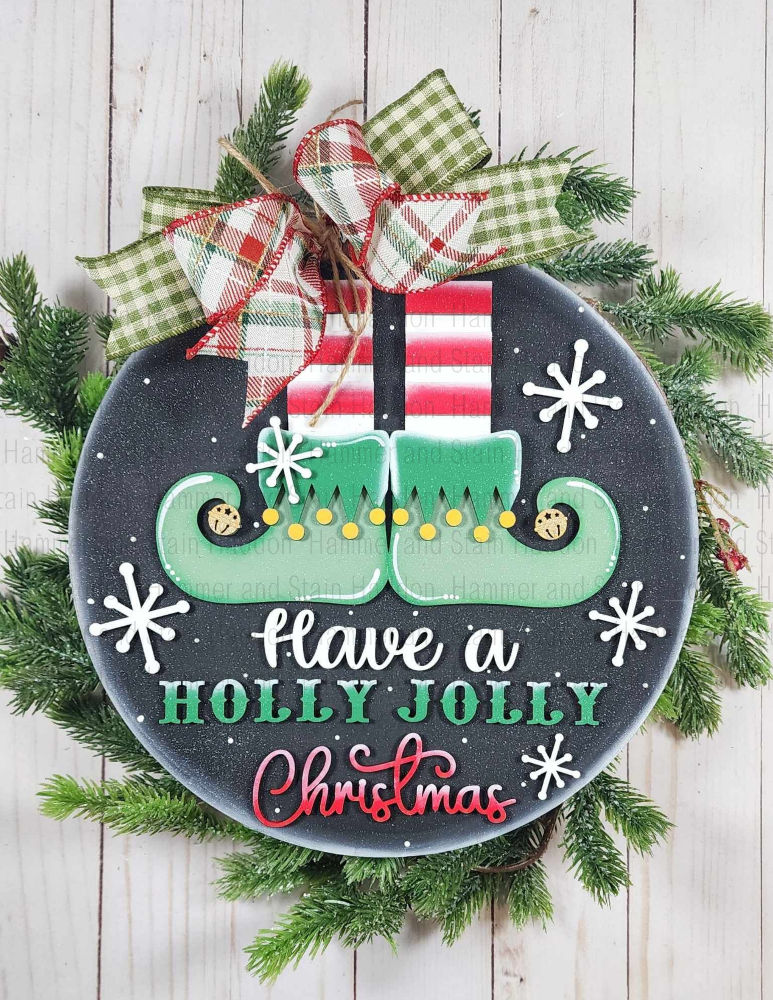 Decorative Christmas sign with elf shoes, holly leaves, and a bow on a wooden background.
