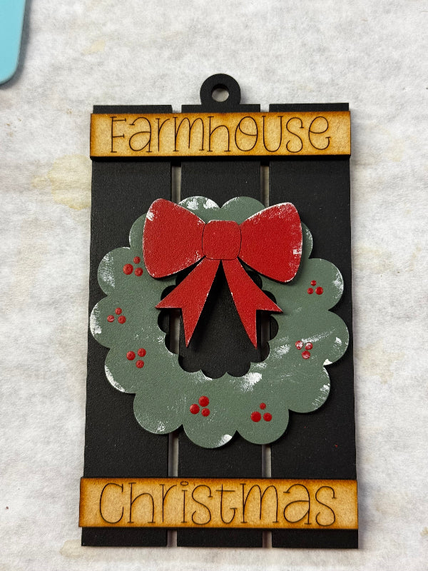 Decorative Christmas Ornament with red bow and 'Farmhouse Christmas' text on a textured surface