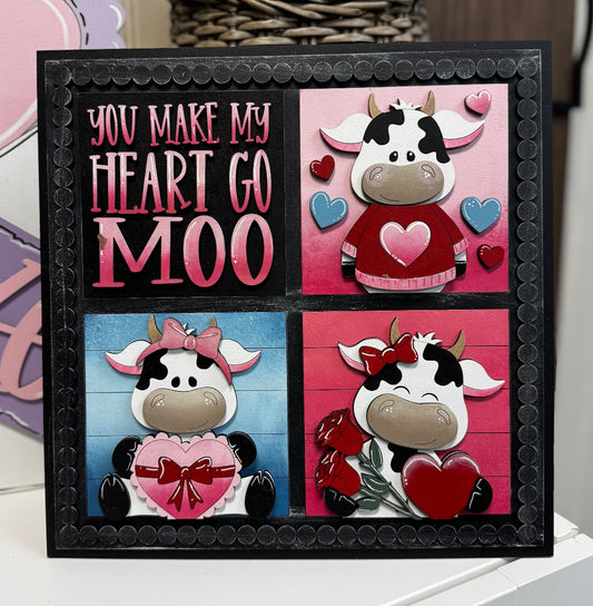 Framed artwork with cow illustrations and text on a white surface