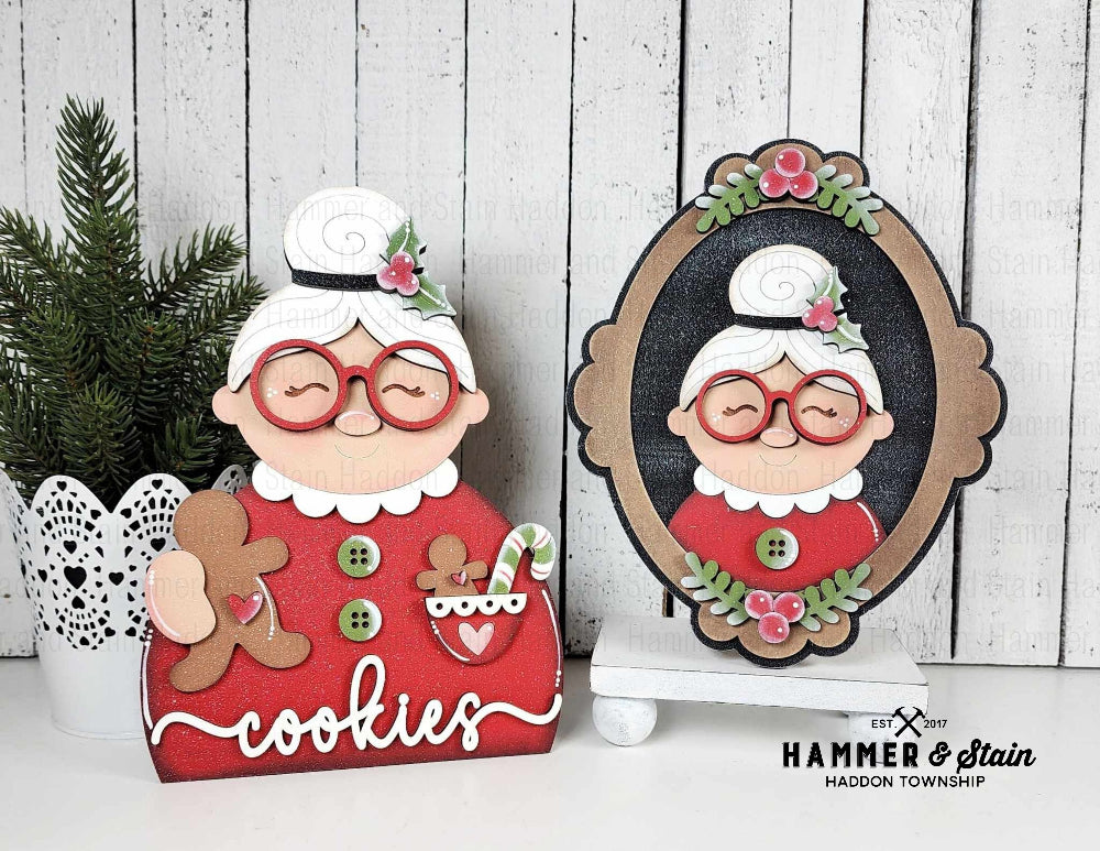 Mrs. Clause shelf sitter design, featuring glasses and a red dress, on a white wooden background and picture frame